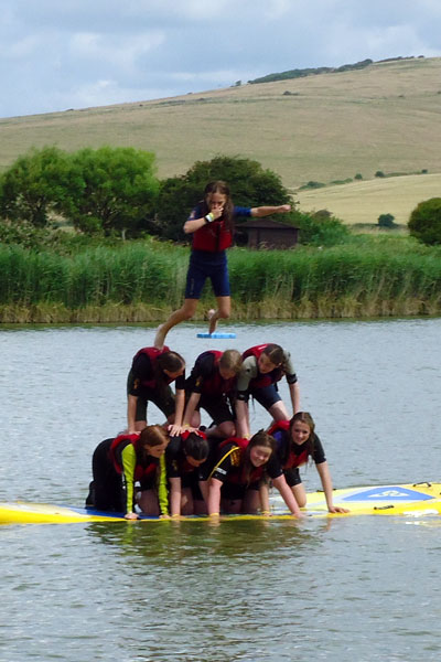 Students creating a human pyramid on floating platform
